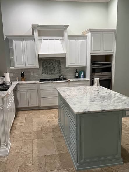 Refinished kitchen with white raised-panel cabinets, a matching painted range hood and a sage-green island under a marble worktop